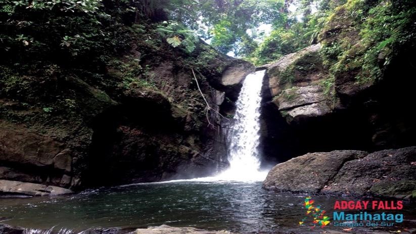 <b class="font-bara"><i class="bi bi-geo-fill h4"></i> Adgay Falls</b> <br/>It is sandwiched with tall green trees and it has clear water flowing down the rocks.